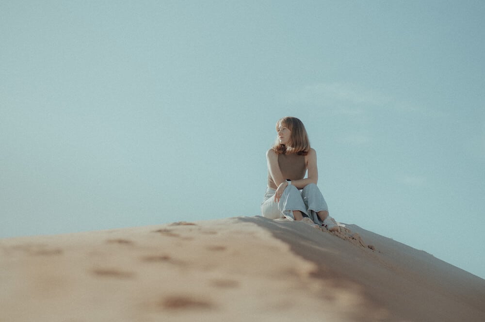 Example of overexposed image woman siting on sand dune